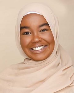 Alia Abdi wearing a cream coloured hijab and smiling, looking forward